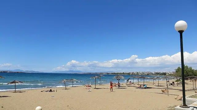 Vouliagmeni Beach in Attica, featuring a sandy shoreline with calm water conditions, certified with Blue Flag status for environmental quality
