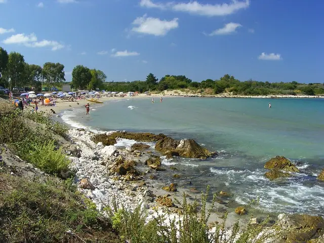 Agios Spyridon Peritheia Beach in Corfu, featuring a sandy shoreline with calm water conditions