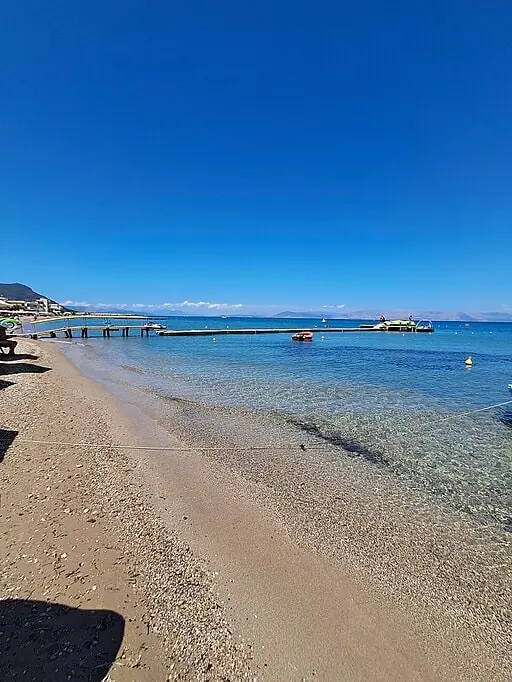 Messongi Beach in Corfu, featuring a mixed shoreline with calm water conditions