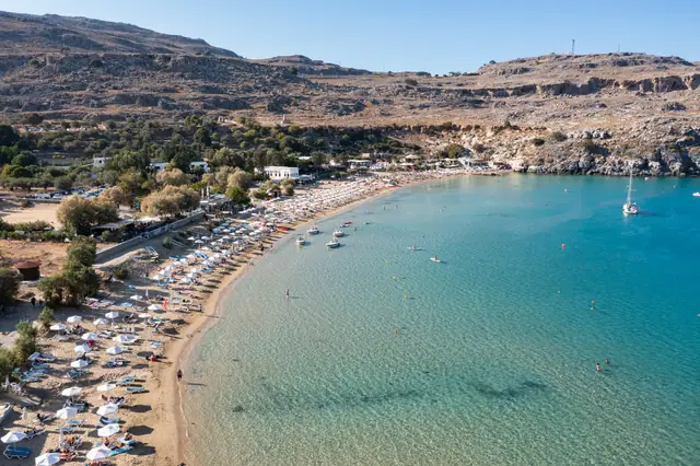 Lindos Beach in Rhodes, featuring a sandy shoreline with moderate water conditions