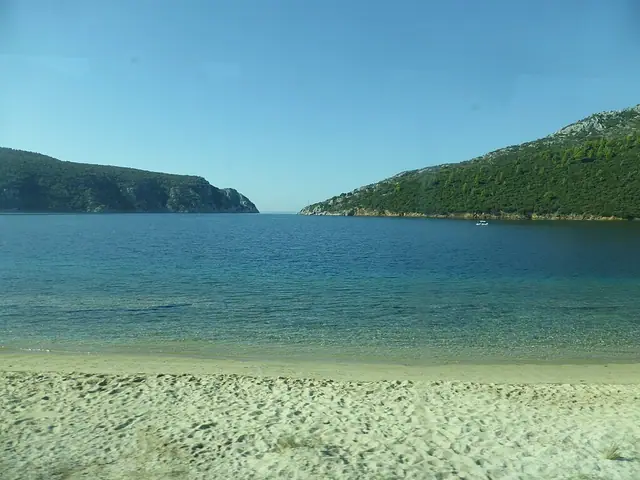Porto Koufo Beach in Chalkidiki, featuring a sandy shoreline with calm water conditions