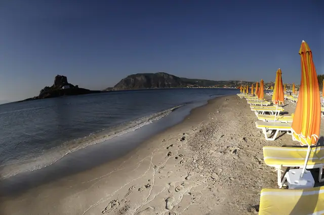 Agios Stefanos Bay beach in Kos, featuring a sandy shoreline with moderate water conditions