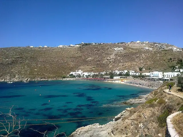 Psarou Beach in Mykonos, featuring a sandy shoreline with calm water conditions