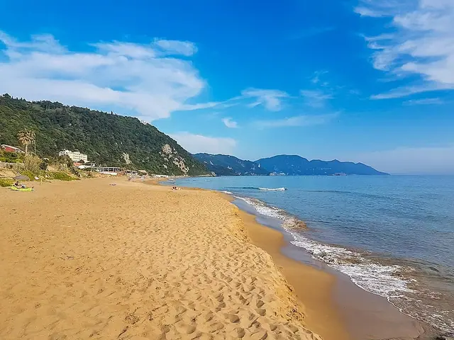 Glyfada Beach in Corfu, featuring a sandy shoreline with calm water conditions, certified with Blue Flag status for environmental quality