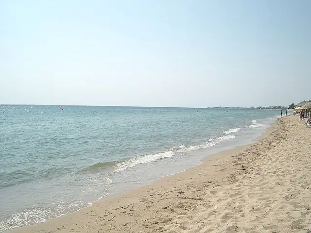 Nea Moudania Beach in Chalkidiki, featuring a sandy shoreline with calm water conditions, certified with Blue Flag status for environmental quality