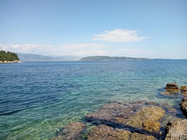 Kalami Beach in Corfu, featuring a pebbly shoreline with calm water conditions