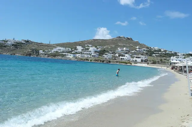 Ornos beach in Mykonos, featuring a sandy shoreline with calm water conditions