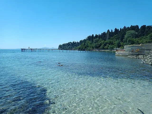 Mon Repos Beach in Corfu, featuring a mixed shoreline with calm water conditions